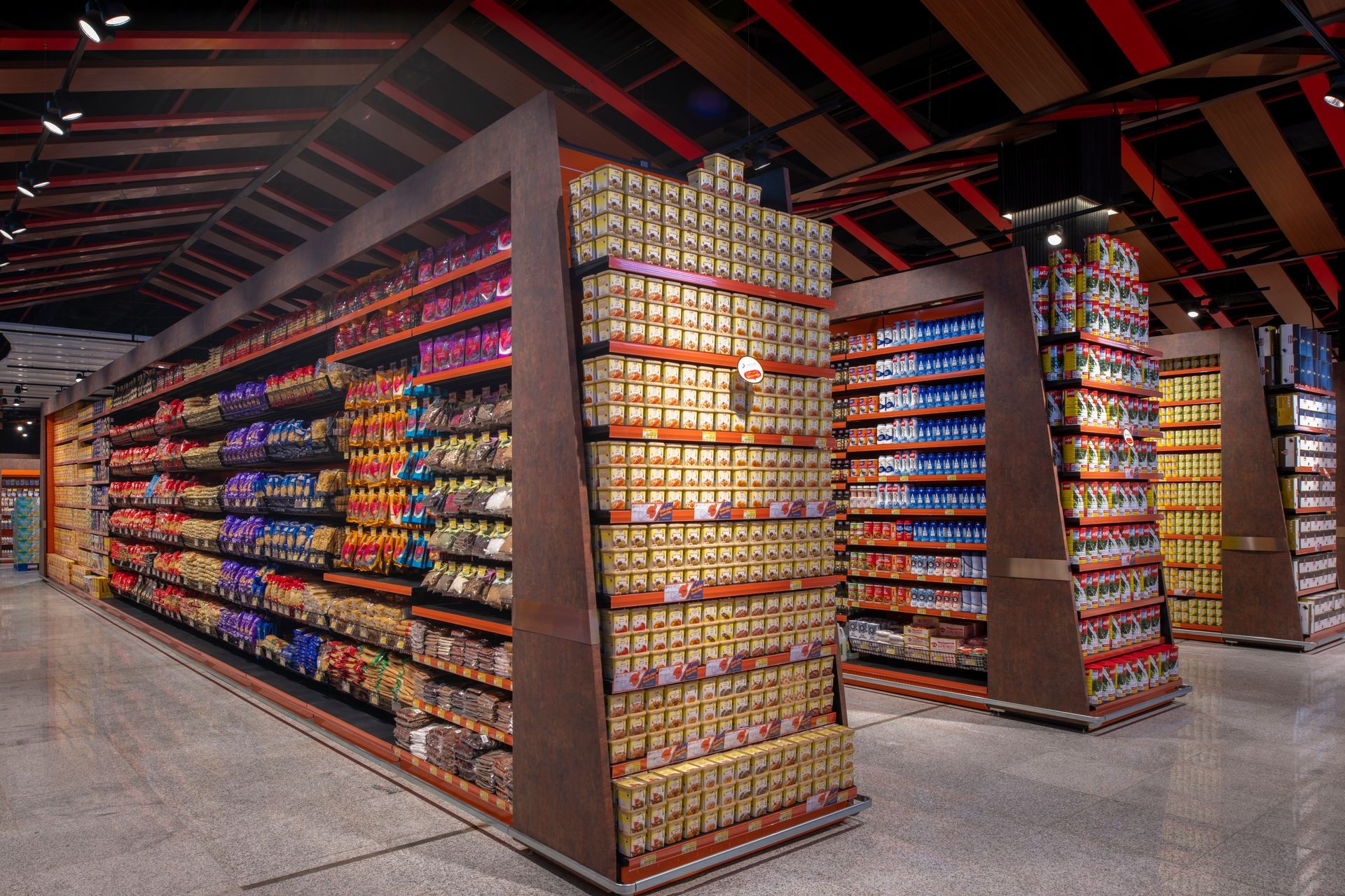 Wide-angle view of a modern supermarket aisle with fully stocked shelves of various packaged food products.